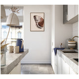 Neutral-toned modern kitchen with gray countertops, white cabinets, a blue pitcher, two mugs, and framed artwork of a brown and black butterfly wing on a beige background.