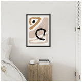 Minimalist abstract art with beige, tan, and black curved shapes framed and hanging above a rustic wooden bedside table holding a white cup and two books.
