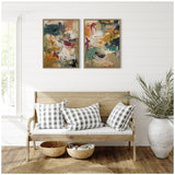 Two abstract paintings with green, mustard, pink, and white brushstrokes in wooden frames above a light wood bench with three black-and-white checkered pillows, woven baskets, and a tall potted plant.