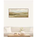 Framed horizontal landscape painting of rolling beige and light green hills beneath a cloudy sky, hanging above a beige sofa with a white pillow and wooden coffee table.
