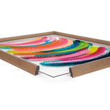 Close-up of colorful abstract brush strokes in pink, blue, green, and orange, displayed in a light wood frame with a visible glass front corner.