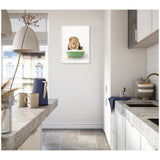 Bright kitchen with concrete countertops and white cabinets, featuring a framed canvas of a lion wearing a flower crown sitting in a green bathtub, centered on a white wall.