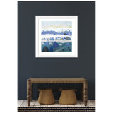 Framed landscape artwork depicting rolling hills and trees in shades of blue, purple, and white against a pale sky, hung on a dark gray wall above a carved wooden bench with two woven baskets beneath.