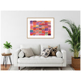 Framed canvas print featuring colorful patchwork of rectangular swatches in shades of pink, red, orange, purple with varied textures, hanging above a white sofa with patterned pillows.