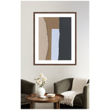 Abstract wall art of overlapping torn paper shapes in beige, brown, light blue, and dark gray, framed in wood and hung above a seating area with dark green chairs and a wooden table.