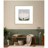 Framed wall art print of a white tulip with green leaves on a muted purple background, hanging above a wooden bench in a softly lit room with sage green wainscoting and beige walls.