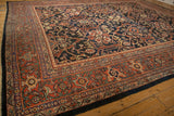 Vintage Mahal carpet with a dark blue field featuring intricate floral and geometric motifs, bordered by multiple bands in red and beige on wooden floor.
