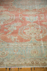 Vintage distressed Mahal carpet in muted coral, light blue, and beige tones with intricate floral and medallion patterns, shown partially from an angled top view.
