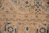 Close-up of a vintage Mahal carpet with faded beige background and blue floral and geometric patterns, showing wear and intricate woven details.
