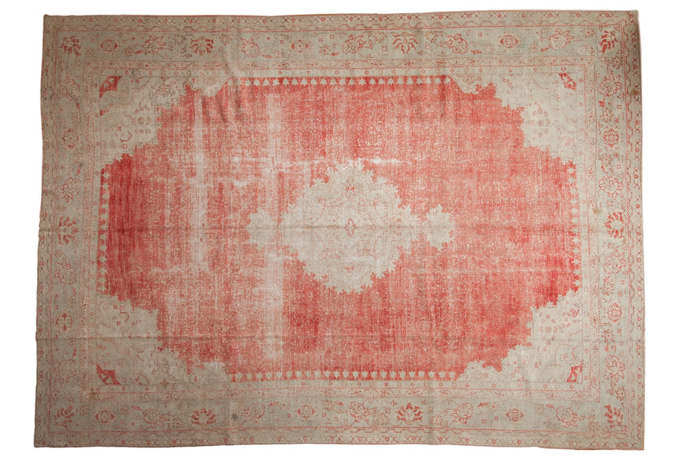 Rectangular vintage Oushak carpet with a faded coral center medallion and beige distressed border featuring subtle floral motifs.