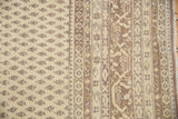 Close-up of a beige and brown vintage Sivas carpet with small repeating floral motifs and intricate geometric border patterns.