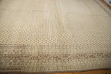 Large cream-colored vintage Sivas carpet with a repeating diamond pattern and intricate floral border in muted brown tones, shown on a wooden floor.
