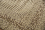Close-up of a vintage distressed Sivas carpet with beige and brown tones featuring geometric and small floral patterns in its border and field.