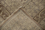 Close-up of a vintage distressed Sivas carpet showing faded geometric patterns in beige and brown tones with worn areas and fringed edges.