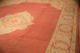 Vintage 12x16 Oushak carpet with a large coral center field and an intricate cream border featuring faded floral motifs.