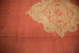 Worn vintage Oushak carpet in muted coral with faded central medallion in light beige and coral accents, showing subtle antique texture.