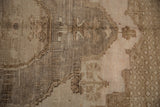 Close-up of a vintage distressed Oushak carpet featuring faded beige and brown tones with intricate geometric and floral patterns.