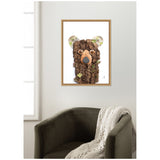 Framed wall art depicting a bear face formed from textured bark and natural elements with subtle green moss accents on a white background, hung above a dark olive armchair.