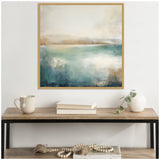 Abstract lake landscape artwork with layered teal, beige, and white hues in a light wood frame above a rustic wood and black metal console table with a beige mug, books, and a white vase with a trailing plant.