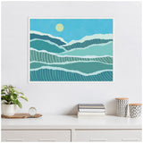 Abstract landscape painting with layered waves in blue and teal tones under a pale yellow sun, framed and hung above a white desk with plants and decor.
