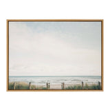 Framed canvas showing a serene beach scene with a calm ocean, pale blue sky, a sandy path bordered by grass and rope fence leading to the water.