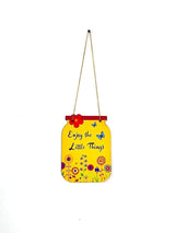 Yellow, jar-shaped wooden wall hanging with red flower and butterfly accents, featuring the black cursive text 'Enjoy the Little Things' above colorful stylized flowers