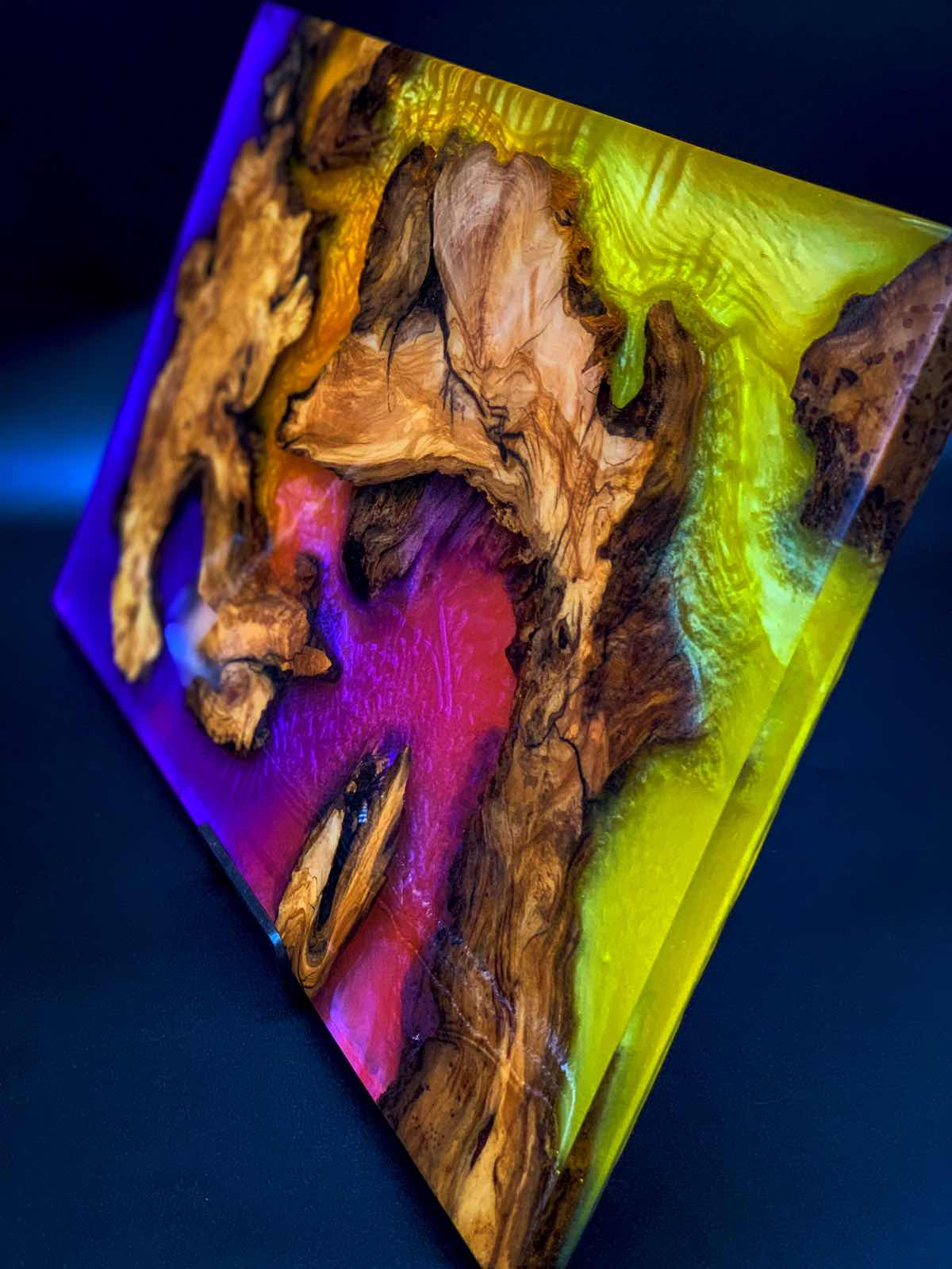 Wooden sculpture with colorful resin on a dark background
