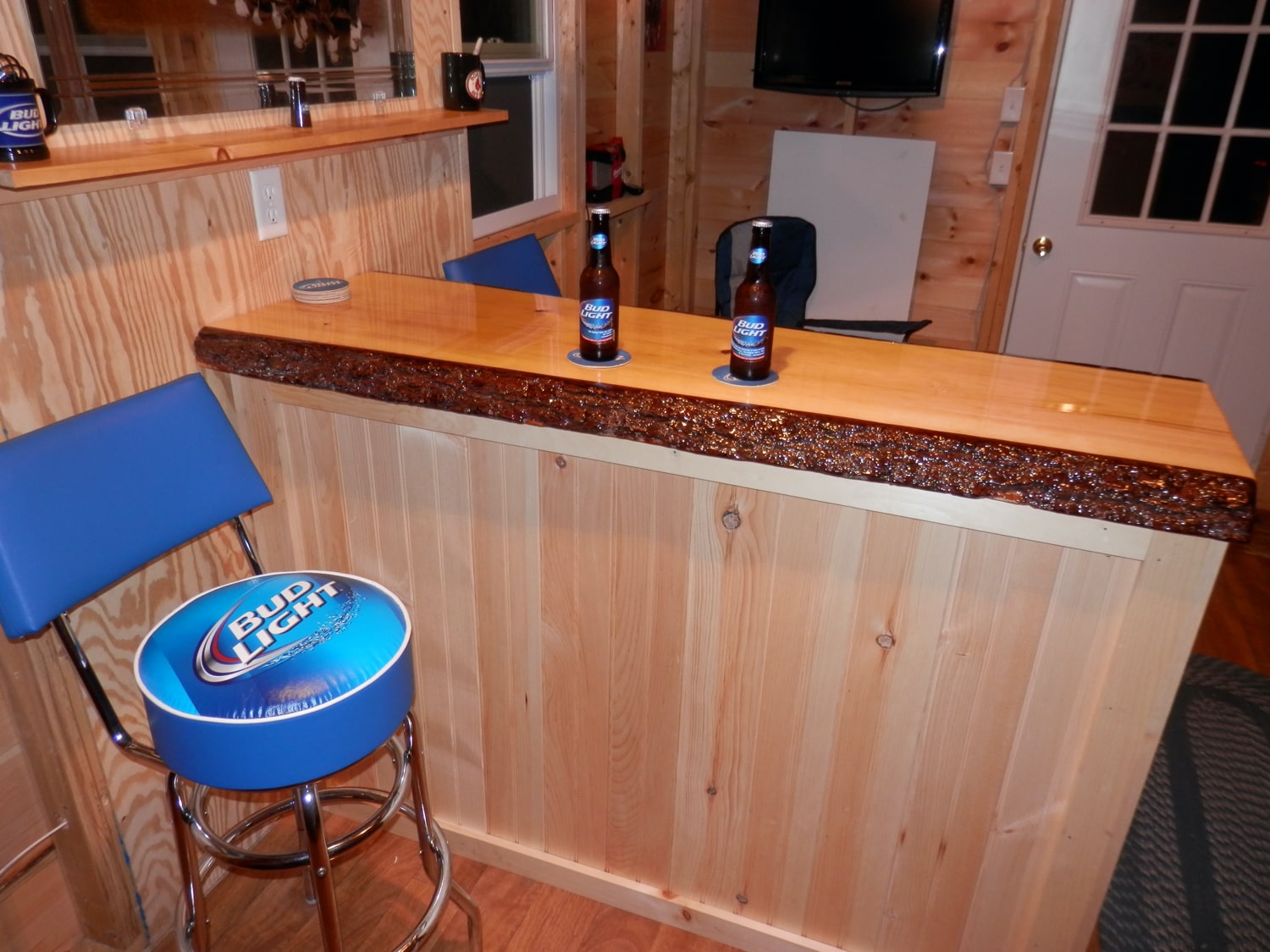 Wooden bar with Bud Light stool and bottles on a wooden floor.