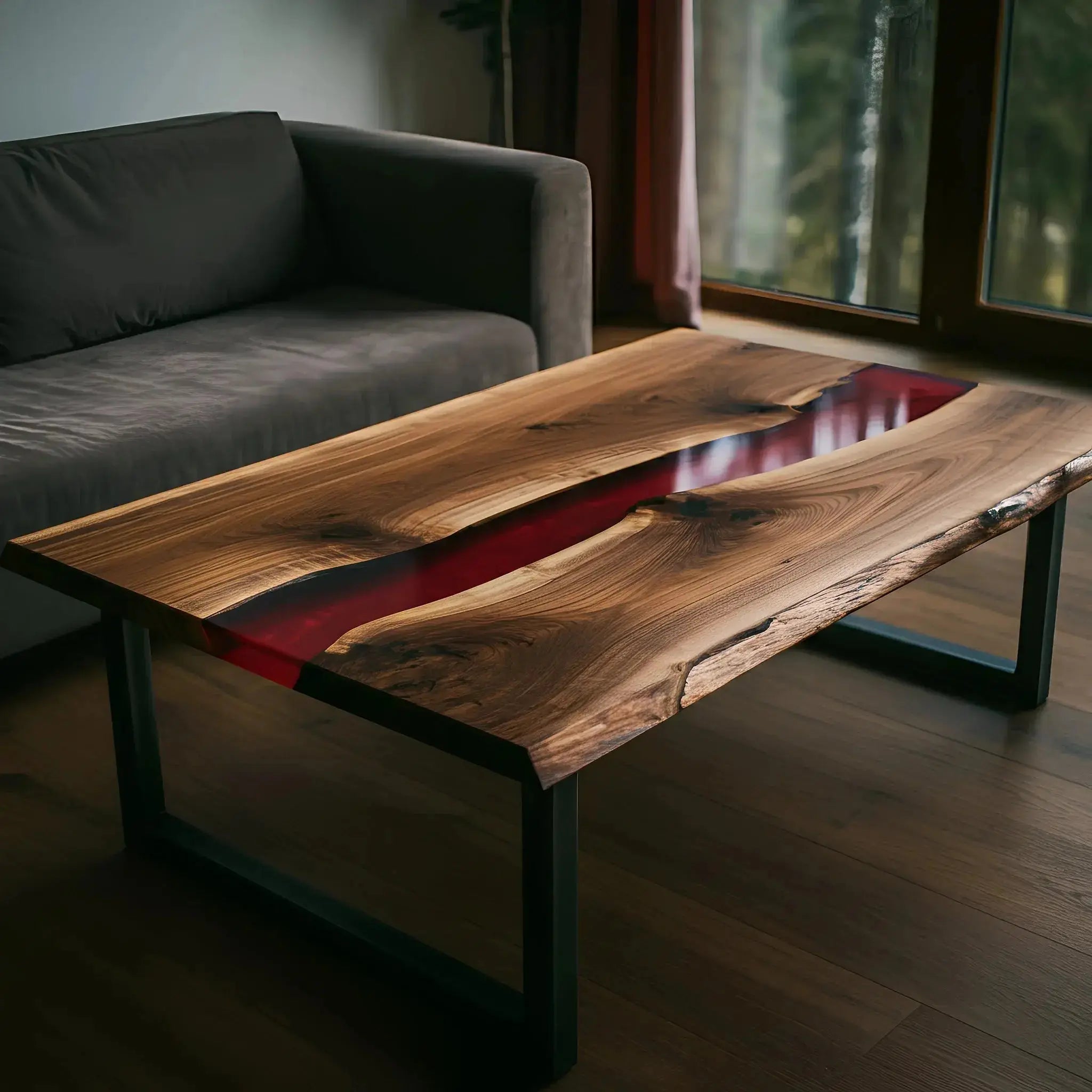 Custom handmade walnut and red resin coffee table beside a gray sofa. Epoxy accent table with natural wood grain and modern design.