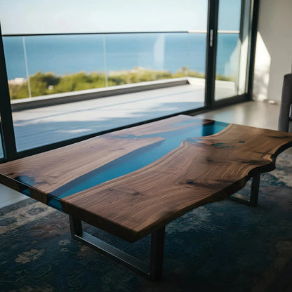 Handmade epoxy coffee table with deep blue resin and walnut wood grain, placed in a modern seaside living room. Custom USA craftsmanship.
