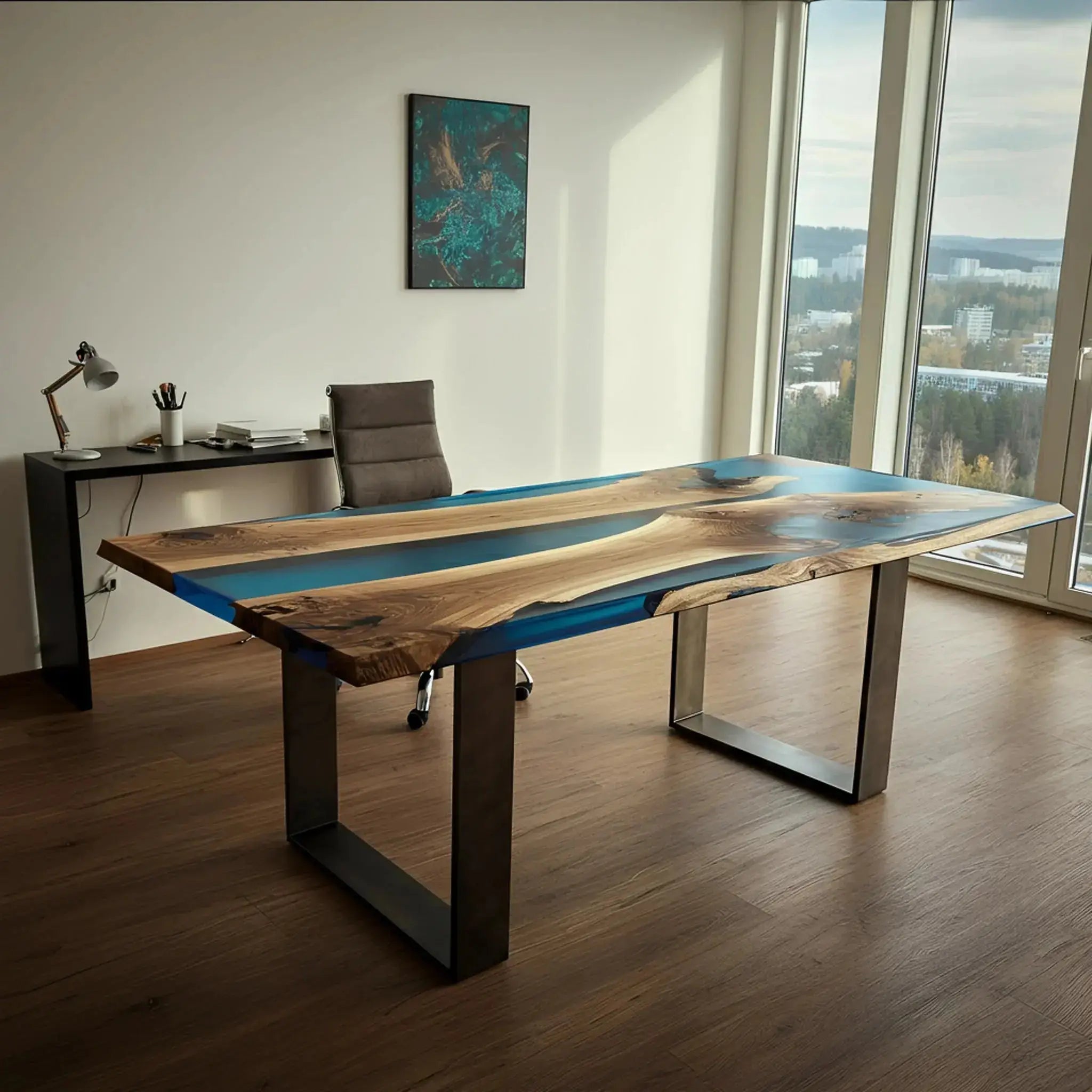 Custom handmade epoxy river desk in walnut and blue resin, placed in a modern office with floor-to-ceiling windows and minimalist decor.