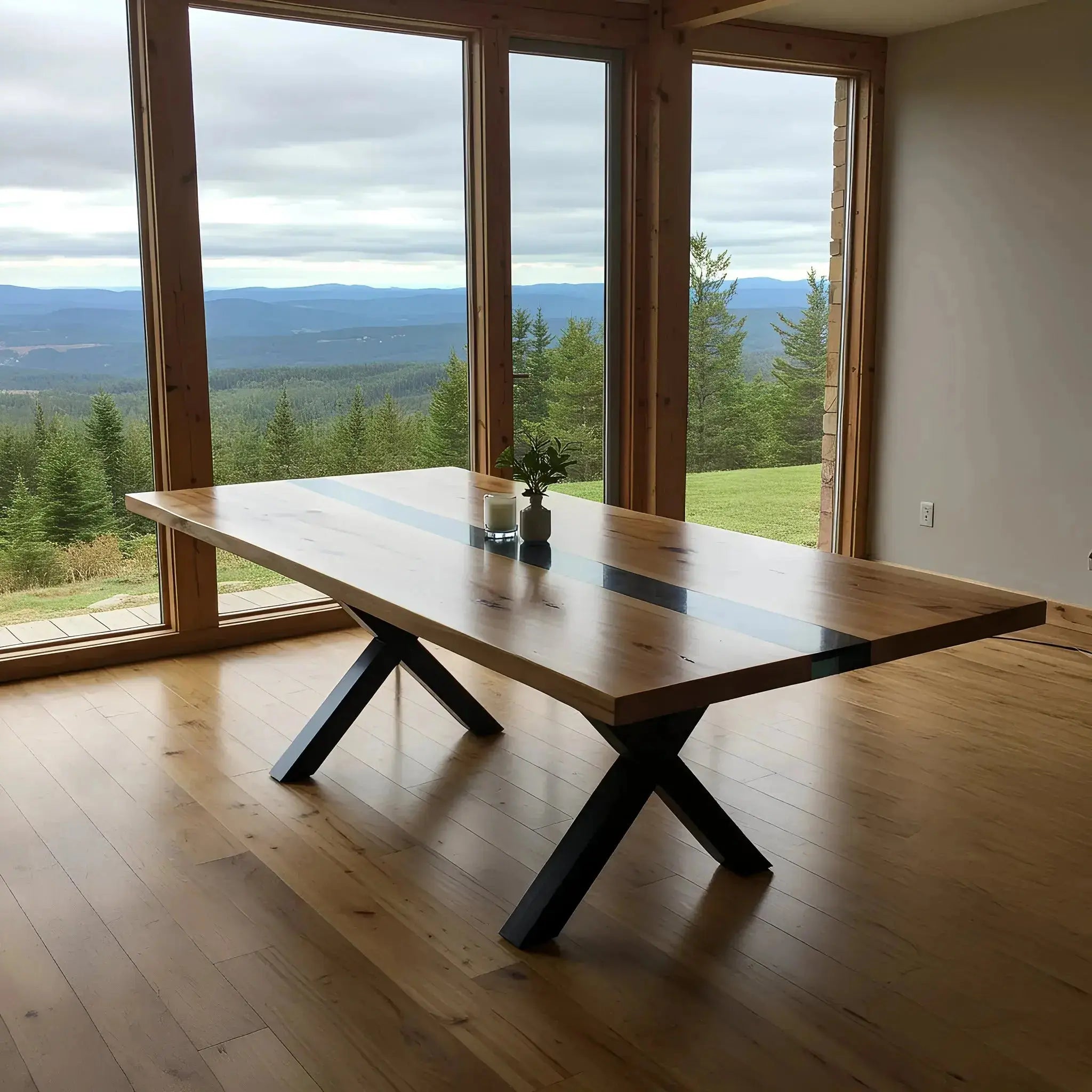 Walnut and black resin custom epoxy dining table with X-shaped metal legs, placed in a minimalist room with panoramic mountain views.
