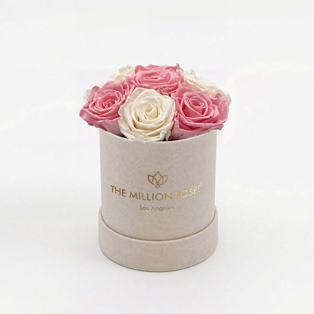 Beige suede box holding light pink and white preserved roses arranged neatly.