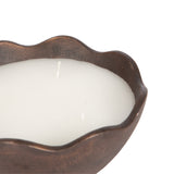 Close-up of a dark brown metal candle bowl with a wavy rim containing white wax and two unlit cotton wicks, shown against a white background.