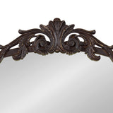Top portion of a traditional arch mirror with a dark brown ornate wood frame featuring carved scrolls and leaf motifs.
