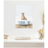 Framed canvas print of a cheetah sitting inside a light blue clawfoot bathtub with a white towel draped over the side and two yellow rubber ducks on a wood floor.