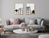 Two framed black-and-white architectural illustrations of Miami Beach buildings with palm trees above a light gray sofa in a modern living room setting.