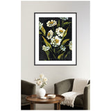 Framed floral painting with white flowers and green leaves on a dark moody background hanging above a round wood table with white vase and two dark gray armchairs, one with a fringed white throw.