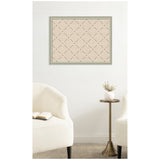 Rectangular pinboard with green frame and beige surface marked by a dark green lattice grid, mounted on a white wall between two white upholstered chairs and a small brass side table with a white vase.