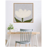 Framed canvas wall art depicting a large white tulip with green stem and leaves set against a muted gray background, hung above a wooden desk and gray chair.