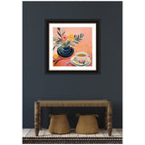 Colorful framed painting showing a black vase with flowers and a patterned teacup on a peach-colored background, hung against a dark gray wall above a wooden bench and two woven baskets.