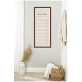 Tall rectangular linen pinboard framed in dark wood, printed like a vintage guest check with columns and blue text, mounted on a light gray wall between white curtain and woven basket