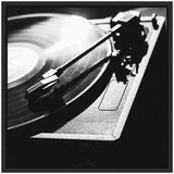 Black and white close-up of a vinyl record player with the needle positioned on a spinning record, emphasizing texture and light contrasts on the turntable surface.