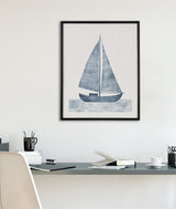 Framed blue sailboat print with textured sails and waves, displayed on a white wall above a minimalist gray desk with white chair and office supplies.