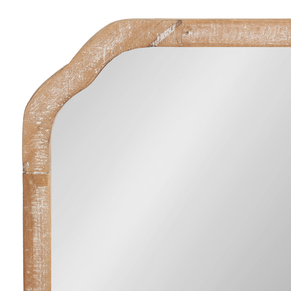 Close-up of a rectangular wall mirror corner with rounded edges and a light brown wooden frame featuring a weathered, distressed finish.