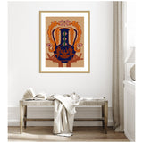 Framed abstract art print featuring a dark blue vessel with orange and pink floral shapes, held by two hands against a beige background, hanging above a wooden bench with a draped white blanket and open book.