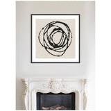 Abstract black concentric circles on beige background in a square black frame above a detailed white decorative fireplace.