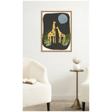 Framed canvas print featuring two stylized yellow giraffes with brown spots standing amidst green leaves under a blue moon on a black background, hanging above a small table.