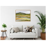 Abstract landscape painting with layered waves of green, beige, and gray hues hanging above a white sofa with patterned cushions, flanked by two green plants in a minimalist room.