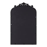 Traditional arched mirror with an ornate black carved frame featuring symmetrical scroll and floral details at the top, shown from the back.